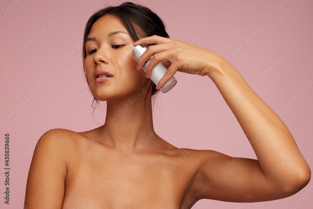 Young woman applying serum to her face