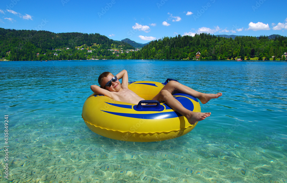 Little boy on inflatable ring in the lake .