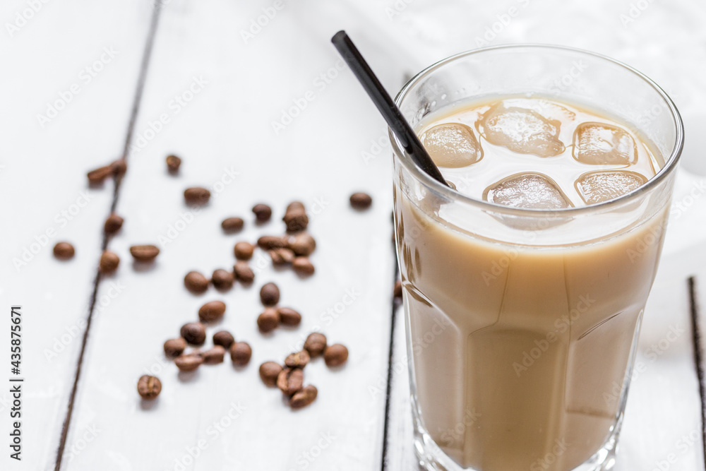 iced coffee with beans for cold summer drink on light wooden background