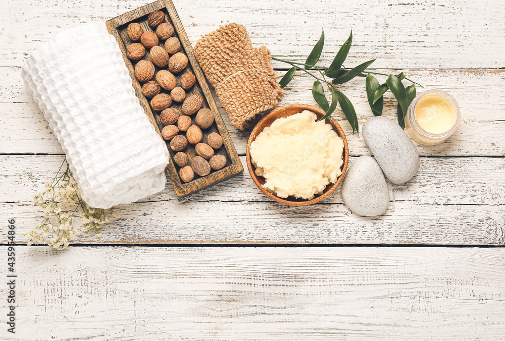 Composition with shea butter, nuts and bath supplies on light wooden background