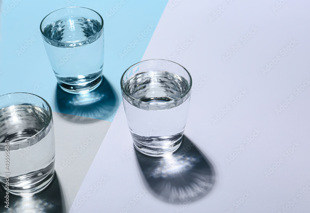 Glasses of water on color background