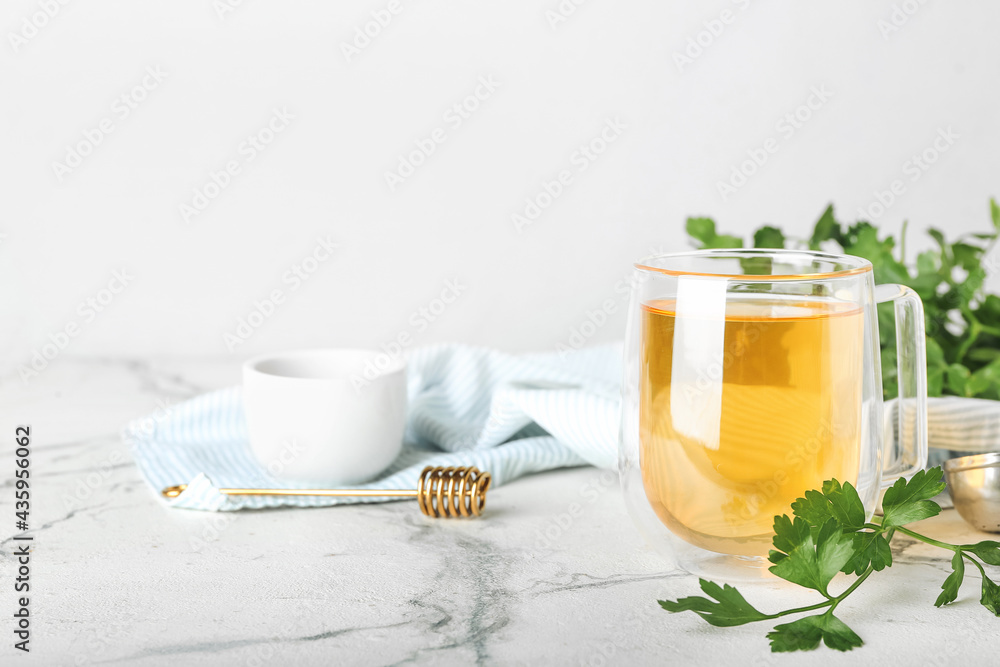 Cup of hot tea, parsley and honey on light background