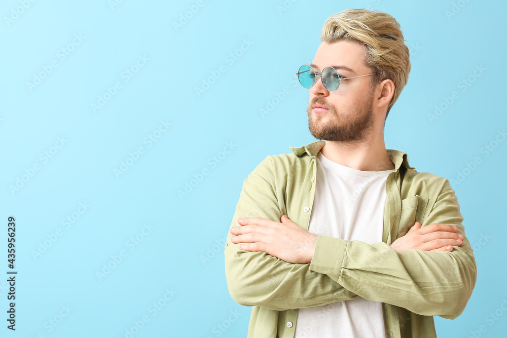 Young man with stylish sunglasses on color background