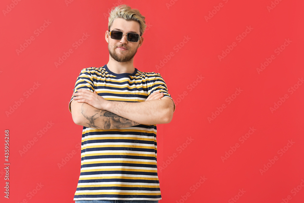 Young man with stylish sunglasses on color background