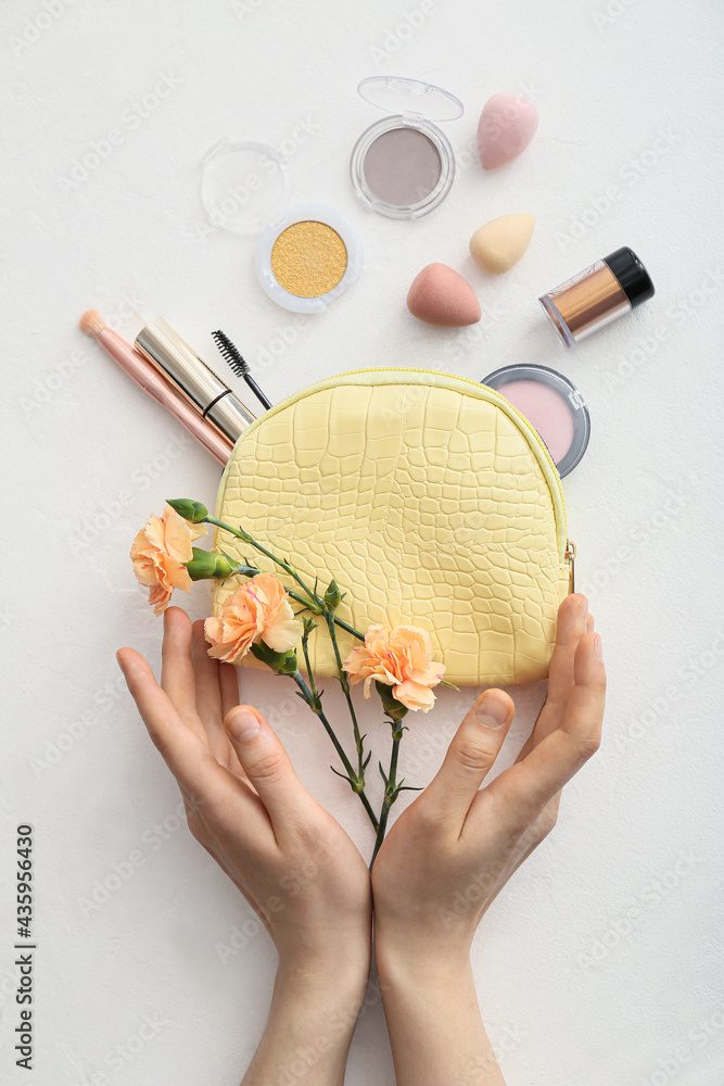 Female hands with stylish bag and decorative cosmetics on light background