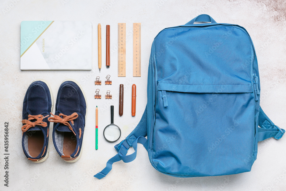 School backpack and stationery on light background