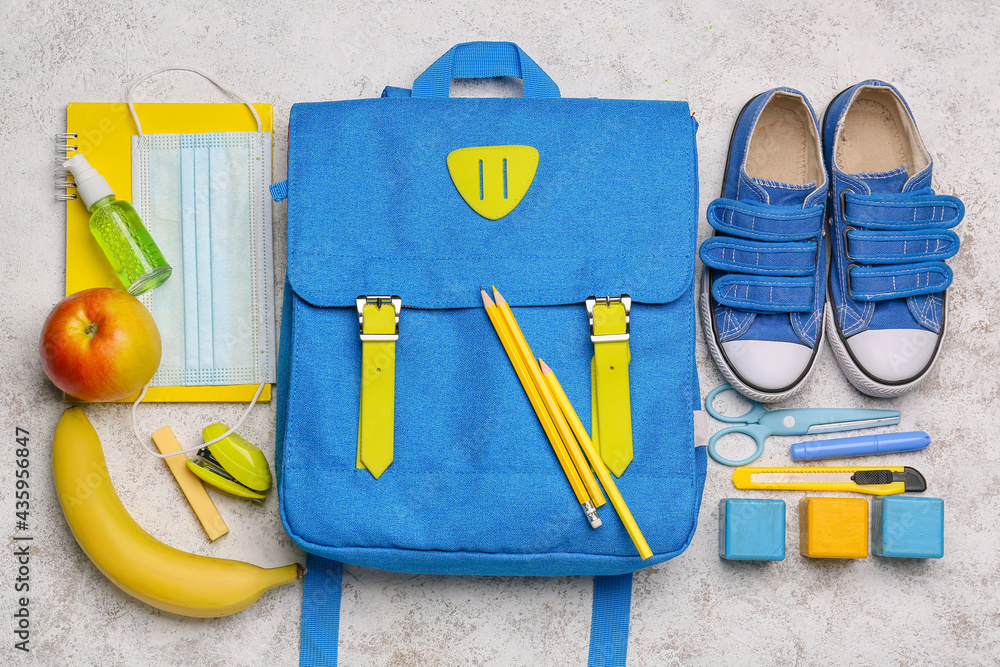 School backpack and stationery on light background