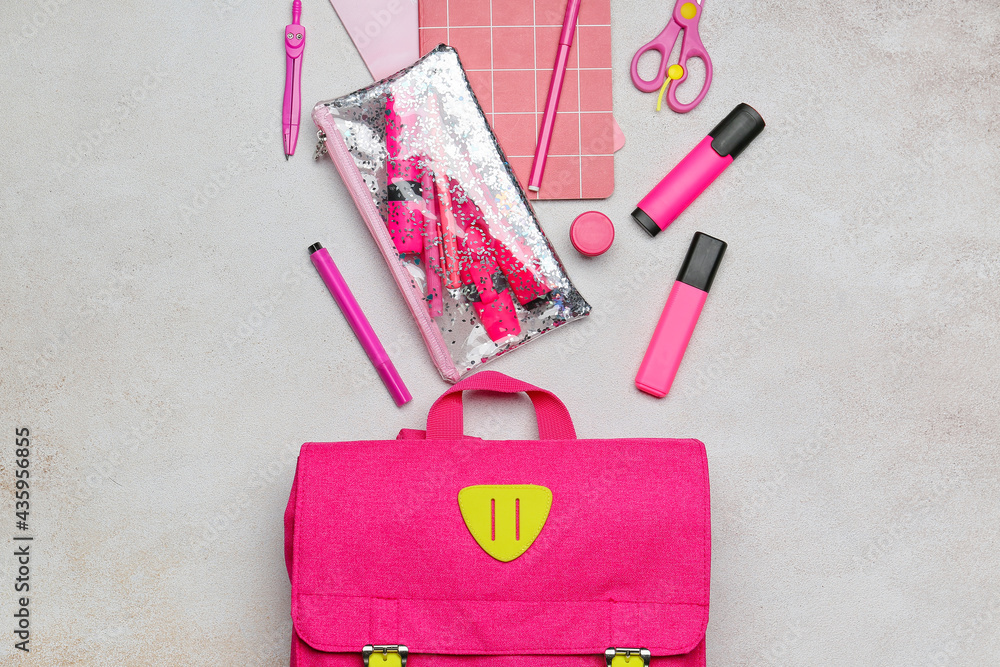 School backpack and stationery on light background