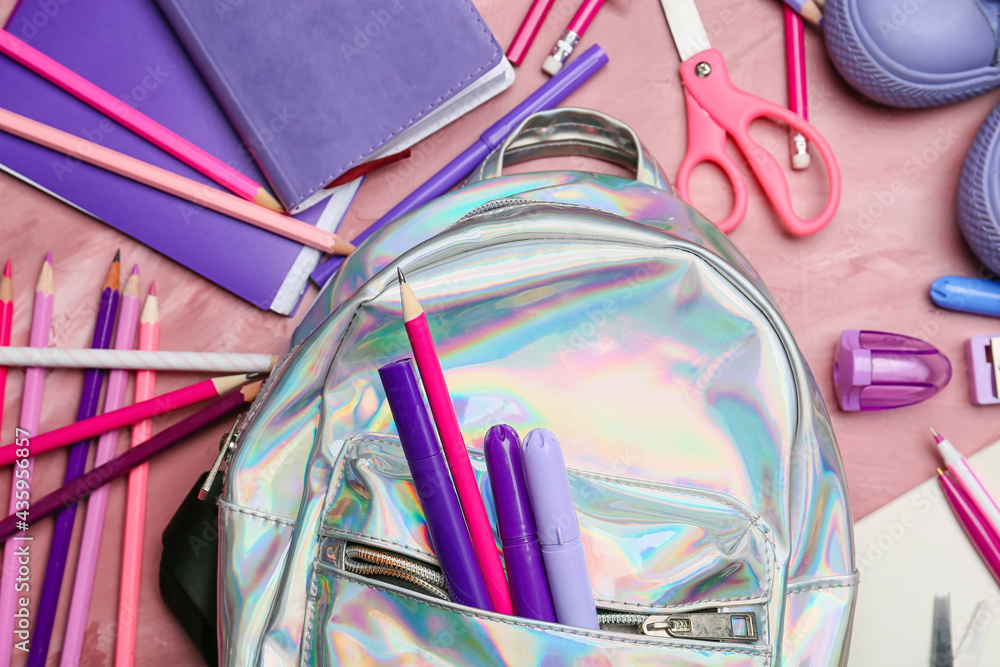 School backpack and stationery on color background