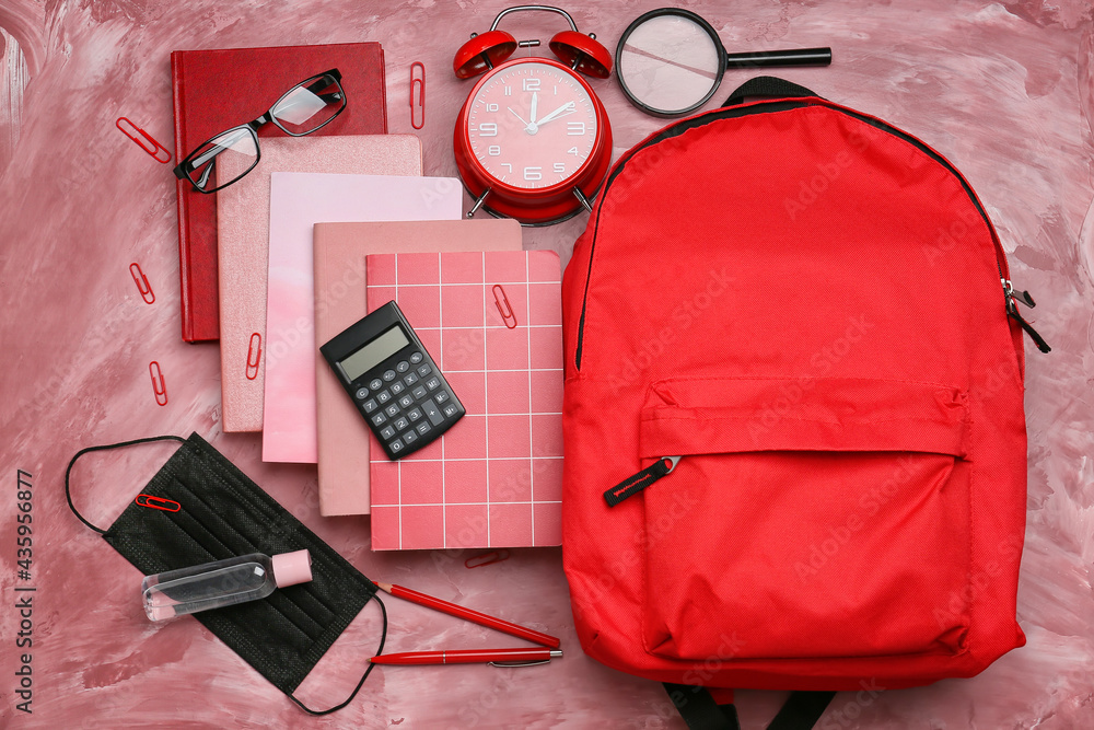 School backpack and stationery on color background