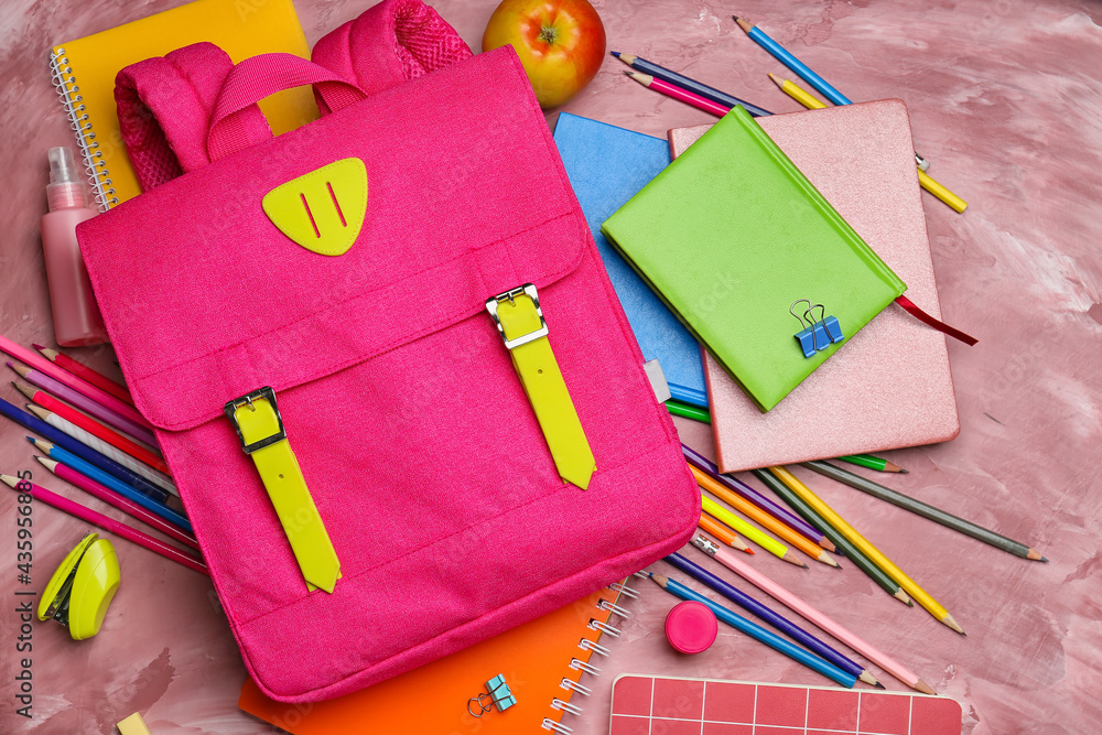 School backpack and stationery on color background