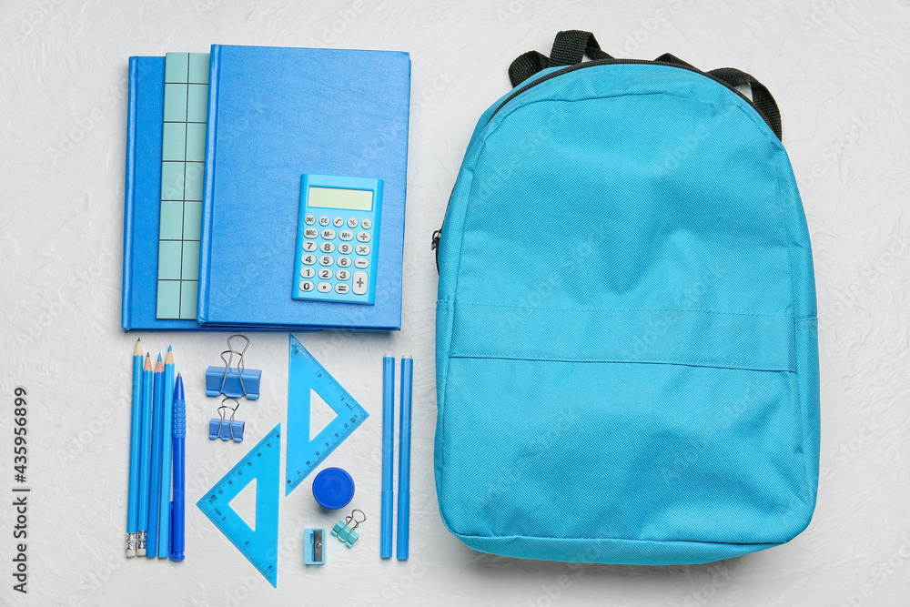 School backpack and stationery on light background