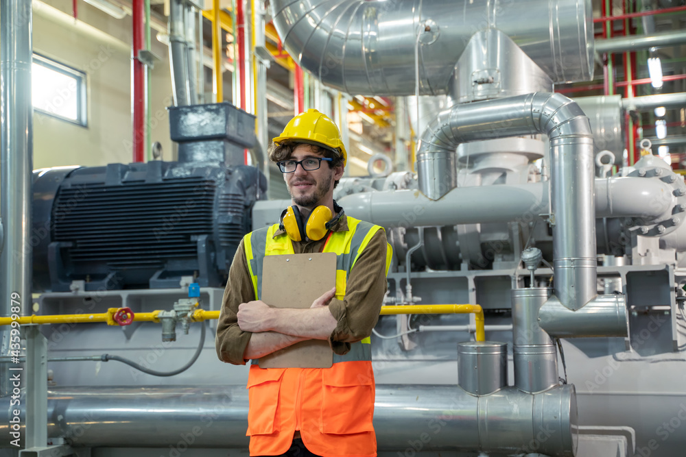 Mechanical maintenance technician inspecting pressure gauge of heating system in heating plant.