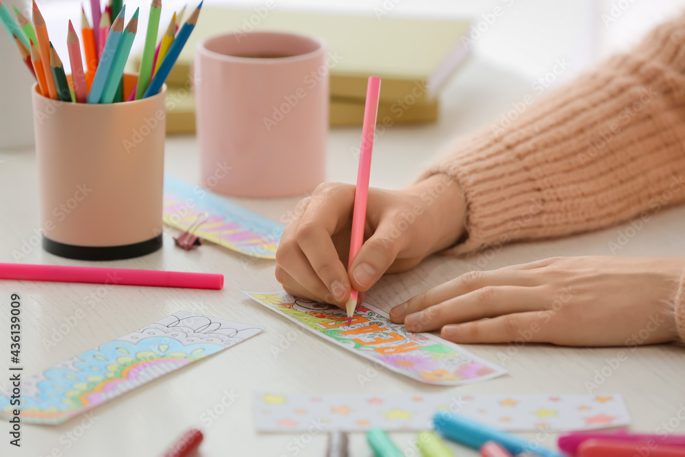 Woman coloring bookmark at table