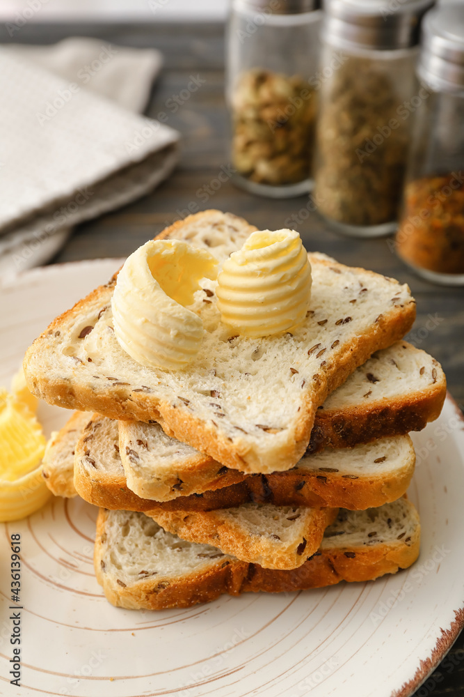 Plate with pieces of fresh bread and butter on table, closeup