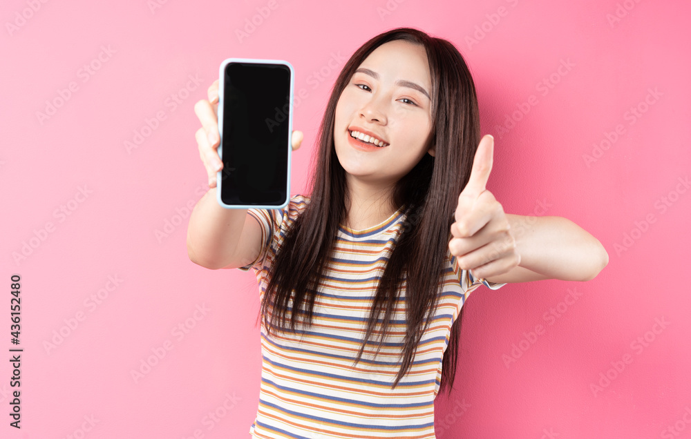 Young Asian woman using smartphone on pink background