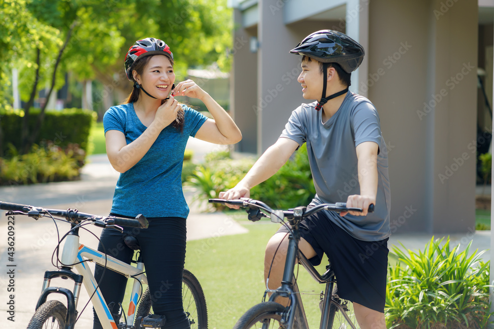 一对亚洲夫妇戴着头盔，准备在附近骑自行车进行日常治疗