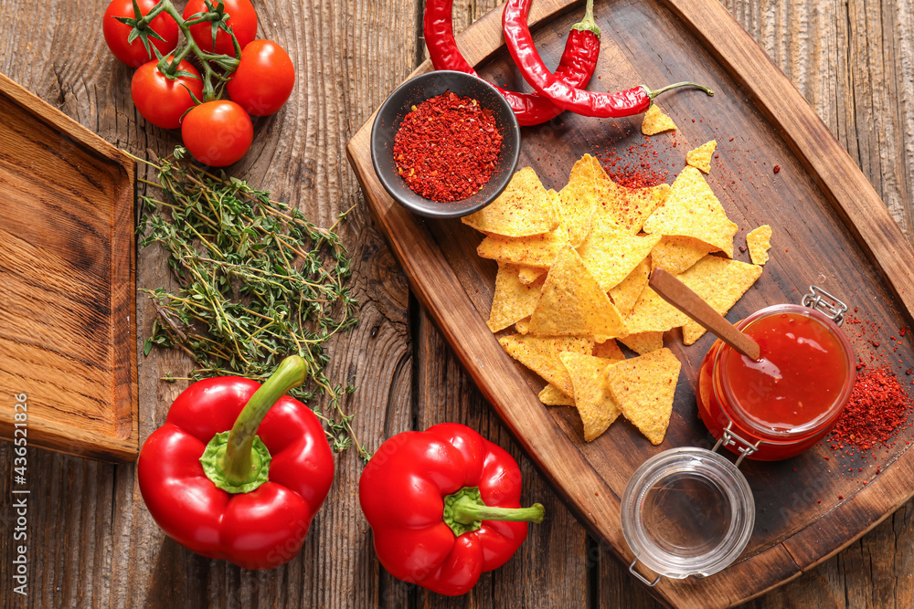 Composition with tasty chili sauce, ingredients and nachos on wooden background