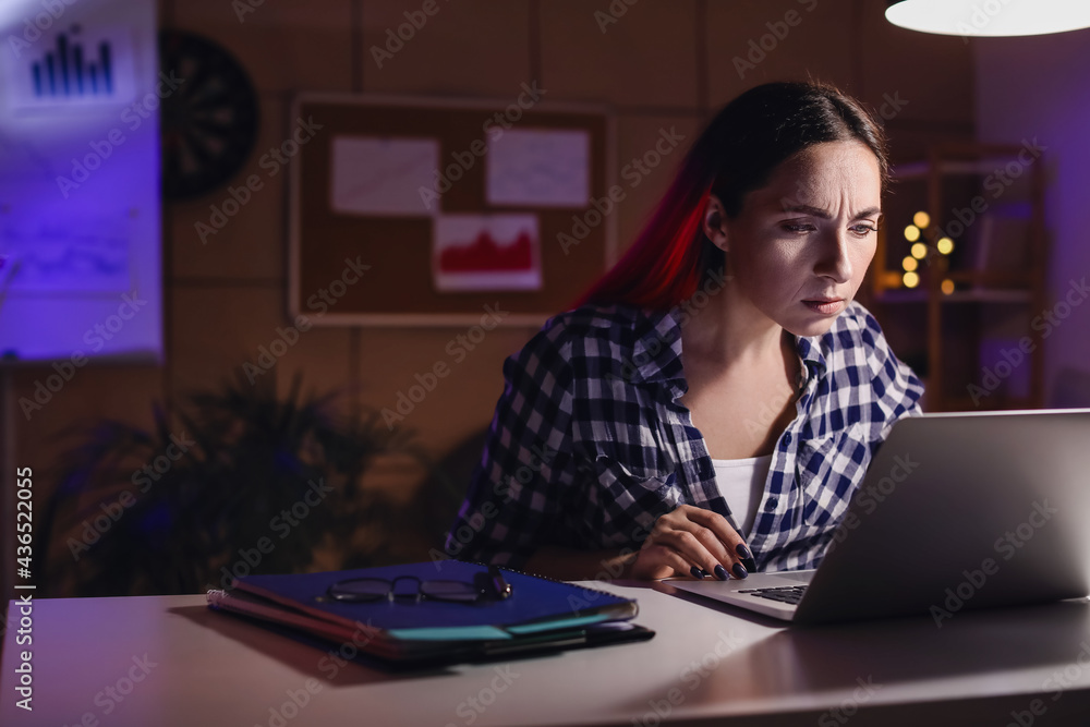 Beautiful woman working with laptop in office at night