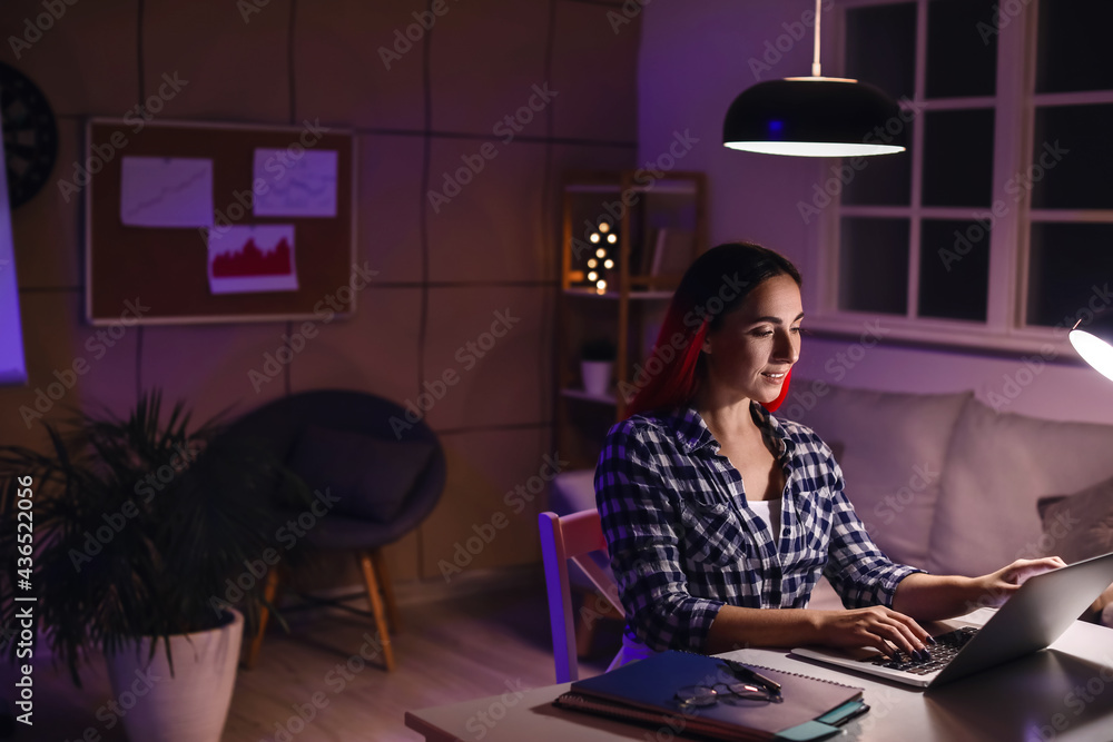 Beautiful woman working with laptop in office at night