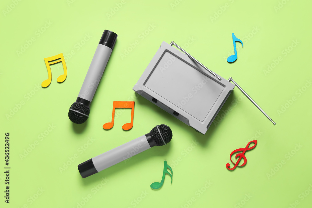 Modern microphones with audio system and music notes on color background