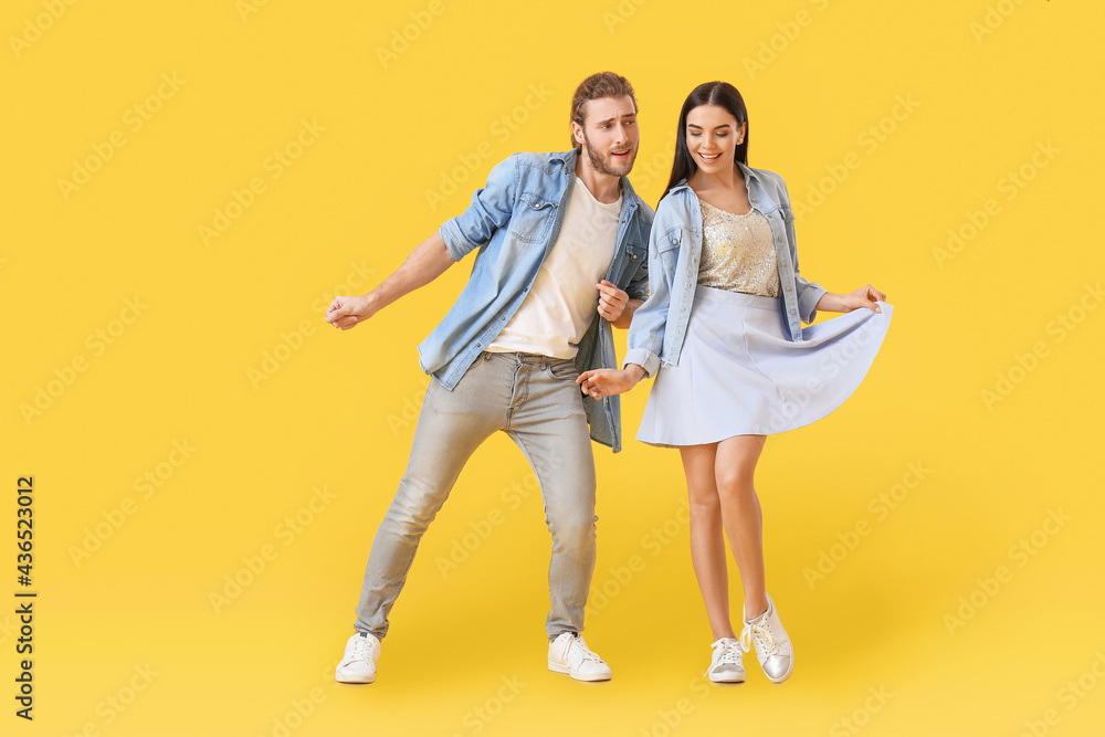 Happy young couple dancing on color background