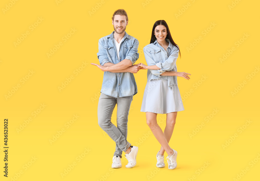 Happy young couple dancing on color background