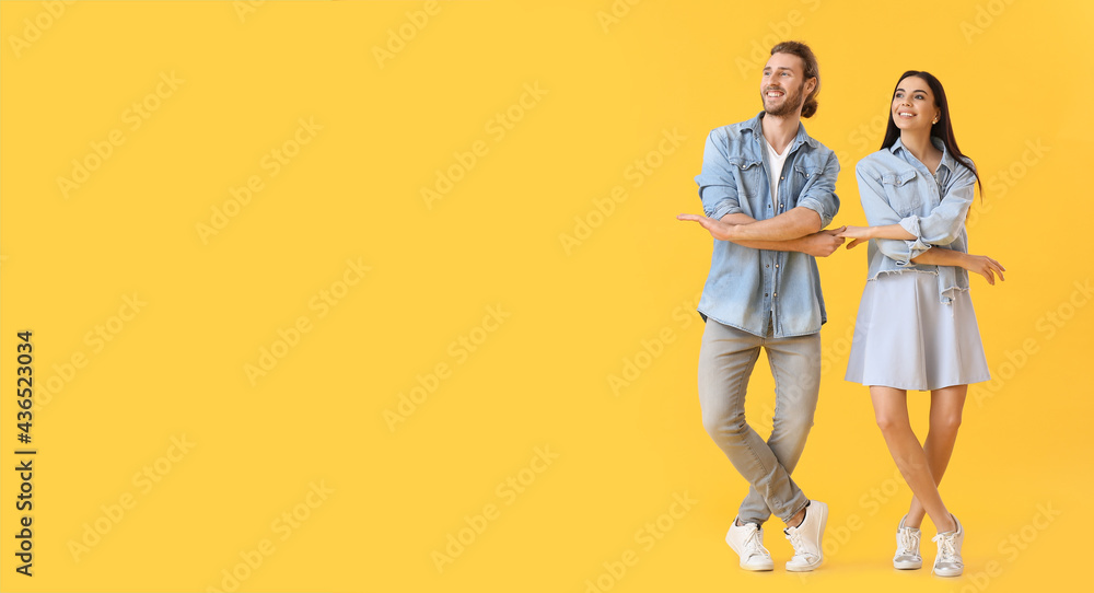 Happy young couple dancing on color background