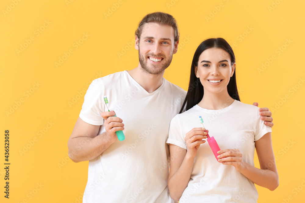 Young couple with tooth brushes on color background