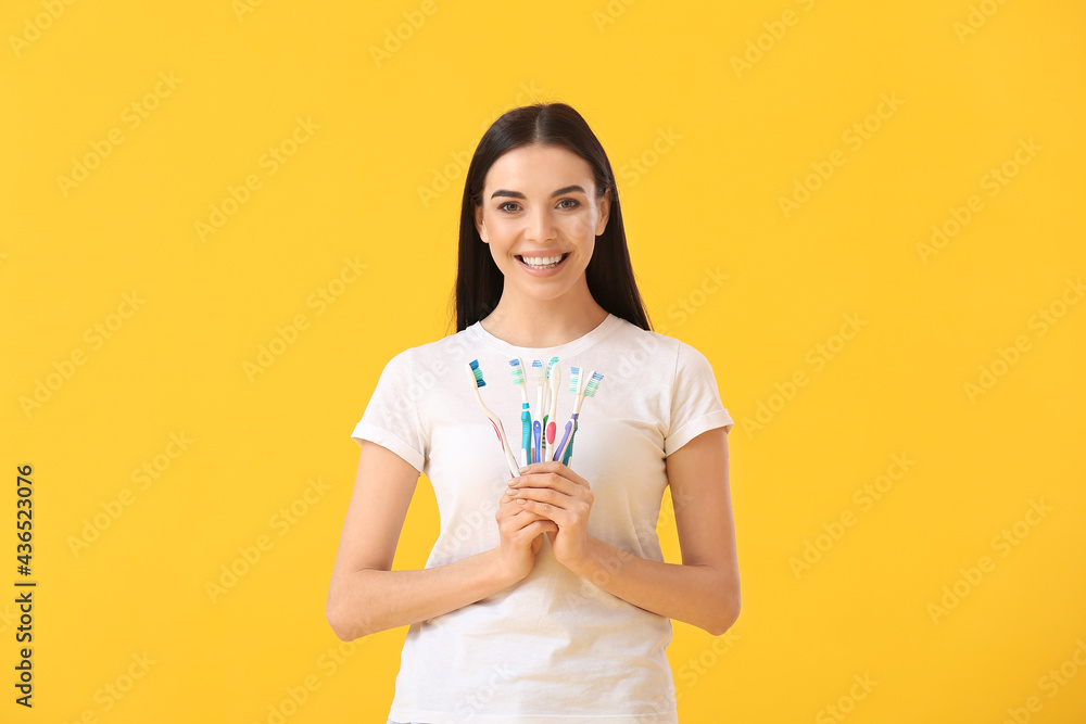 Young woman with tooth brushes on color background