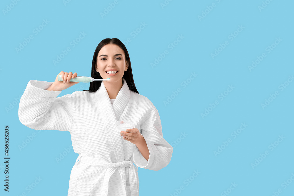 Young woman brushing teeth on color background