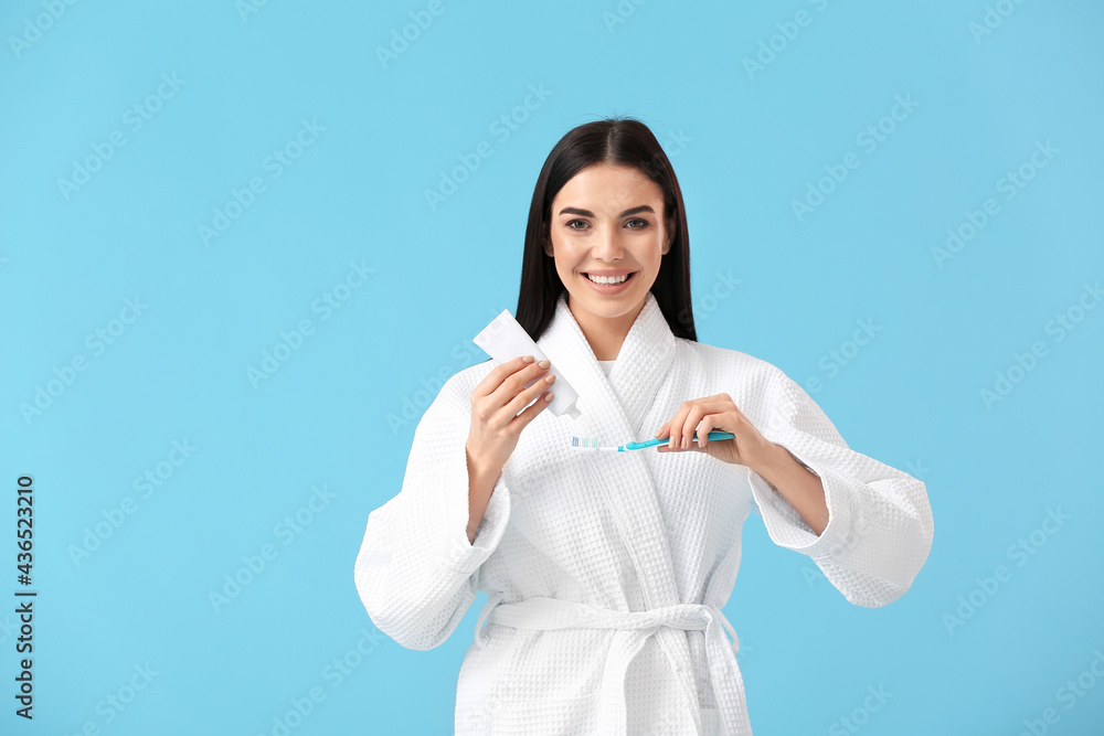 Young woman brushing teeth on color background