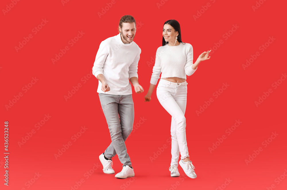 Happy young couple dancing on color background