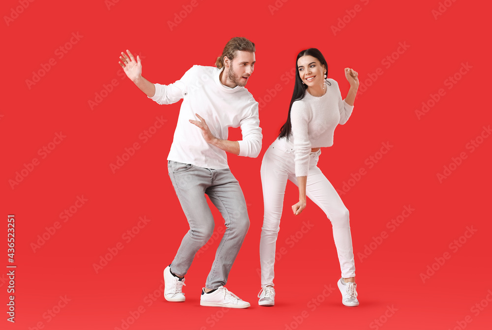 Happy young couple dancing on color background