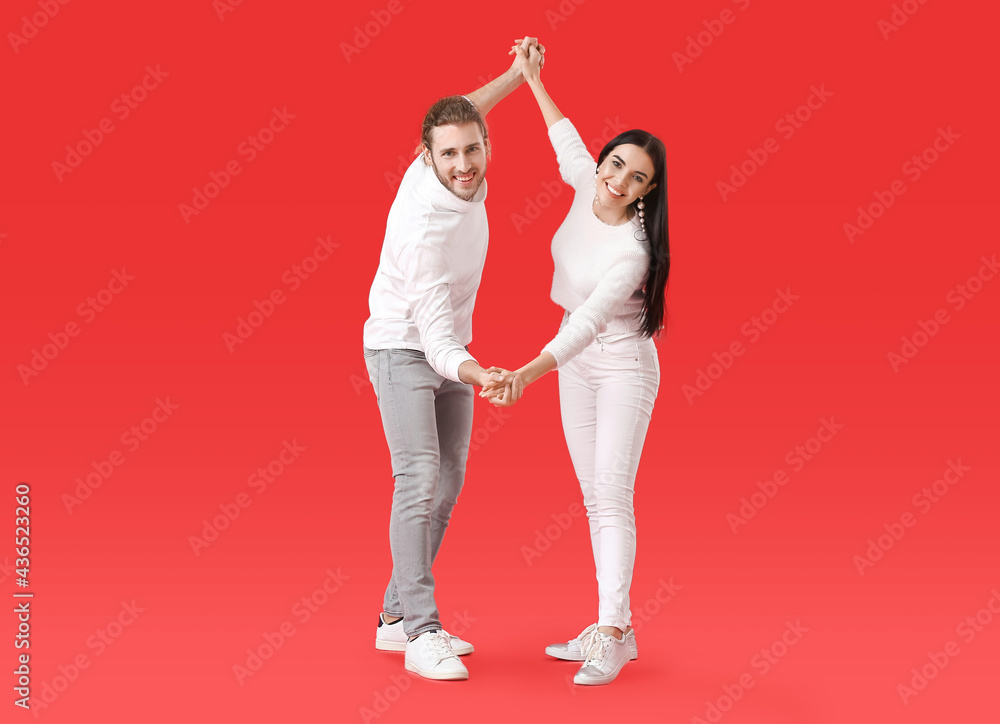 Happy young couple dancing on color background