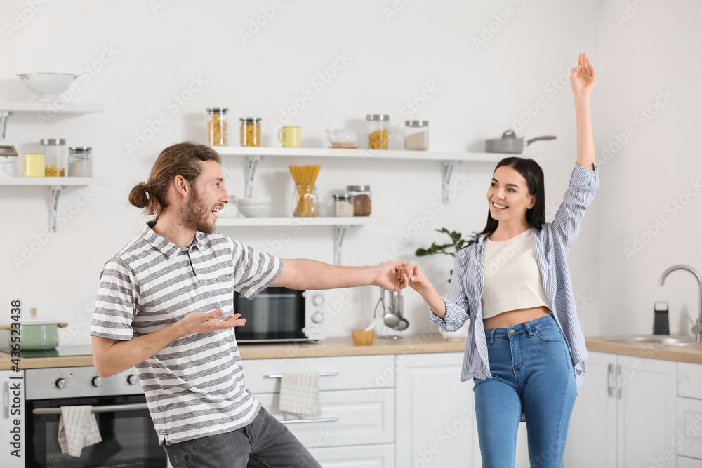 Happy young couple dancing in kitchen