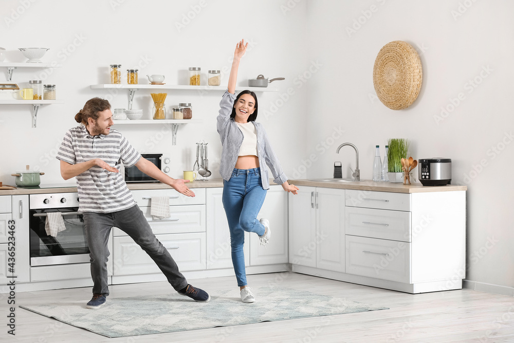 Happy young couple dancing in kitchen