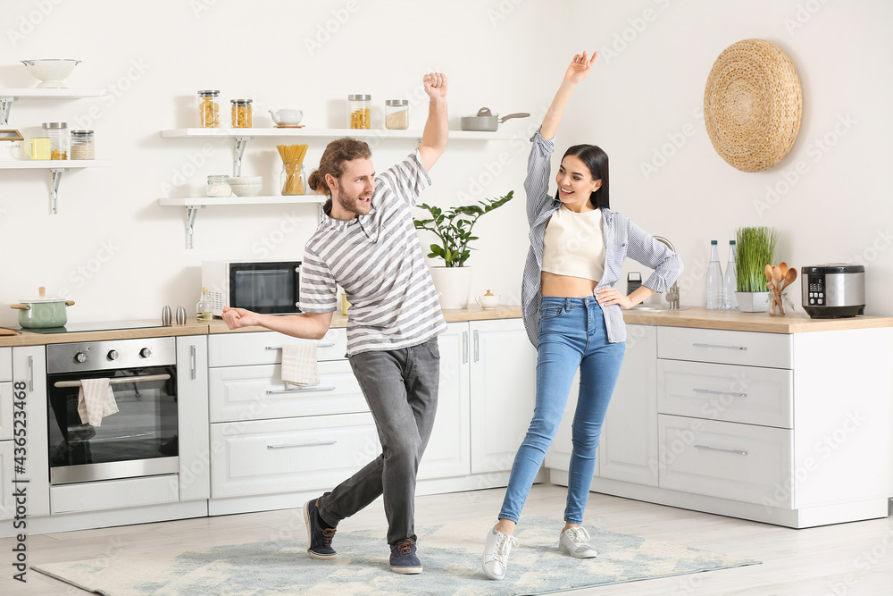 Happy young couple dancing in kitchen