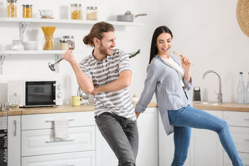 Happy young couple dancing in kitchen