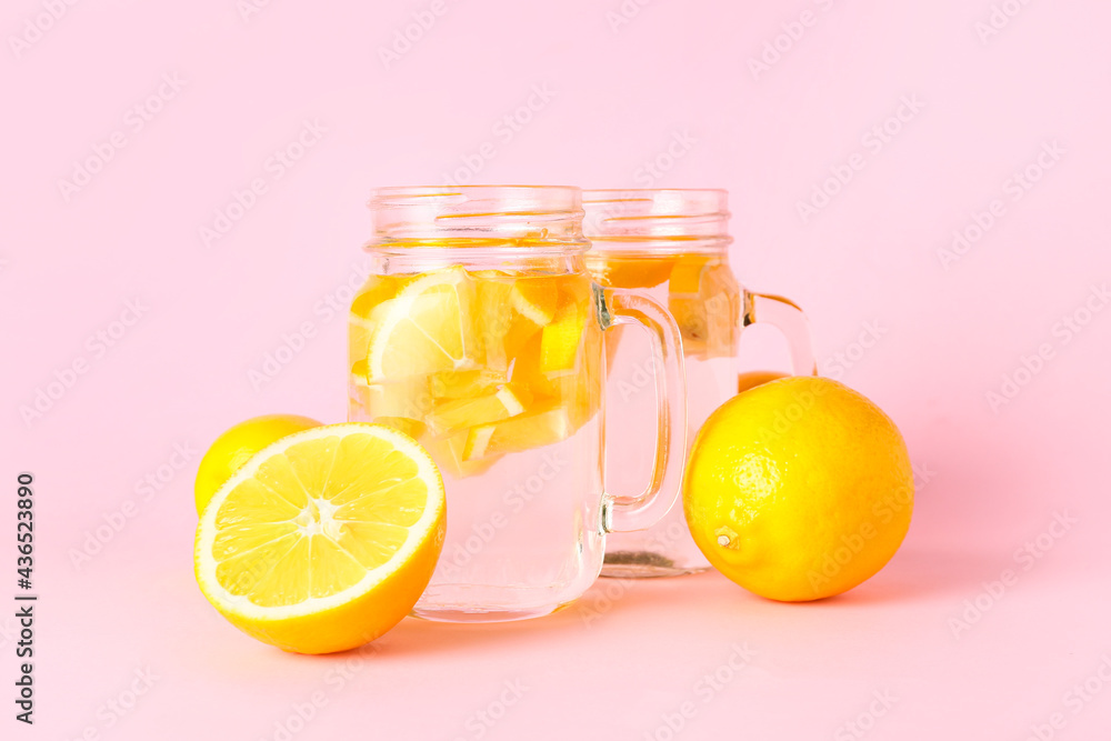 Mason jars of tasty cold lemonade on color background