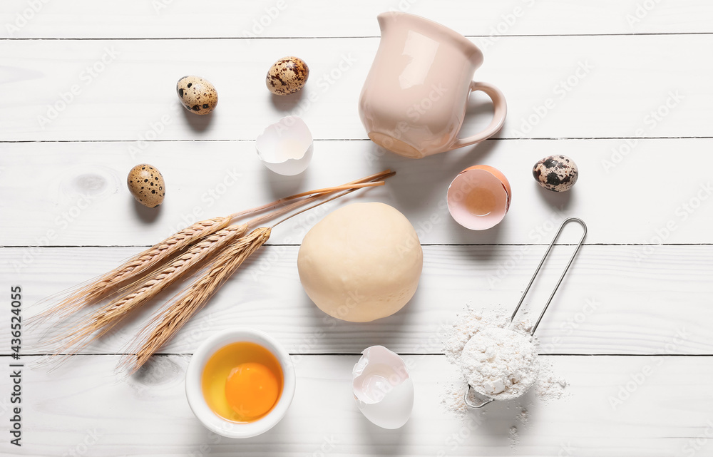 Composition with fresh dough, flour and eggs on light wooden background