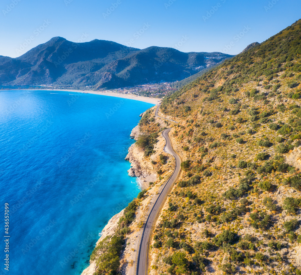 蓝色大海附近的山路鸟瞰图，夏日日落时的沙滩。土耳其奥卢代尼兹。Top v