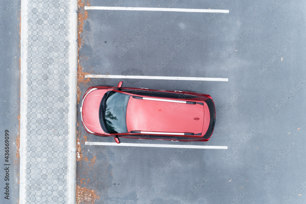 Aerial view top down of red SUV car parked at concrete car parking lot with white line of traffic si