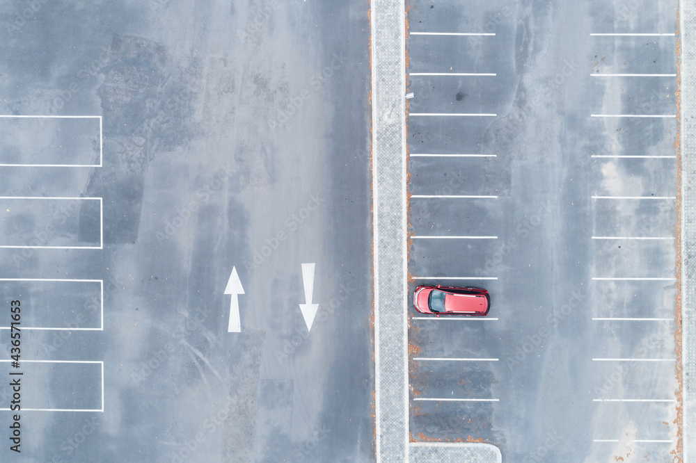 Aerial view top down of red SUV car parked at concrete car parking lot with white line of traffic si