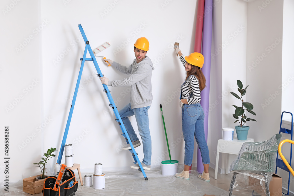 Happy young couple painting wall in their new house