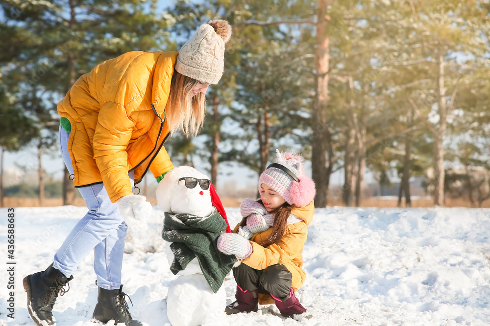 Happy family making snowman in park