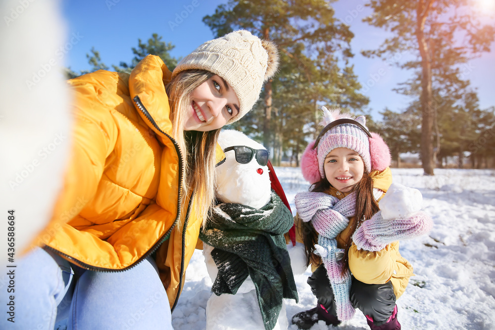 Happy family taking selfie with snowman in park