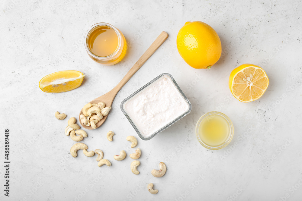 Bowl with cashew sour cream, nuts, honey and lemon juice on light background