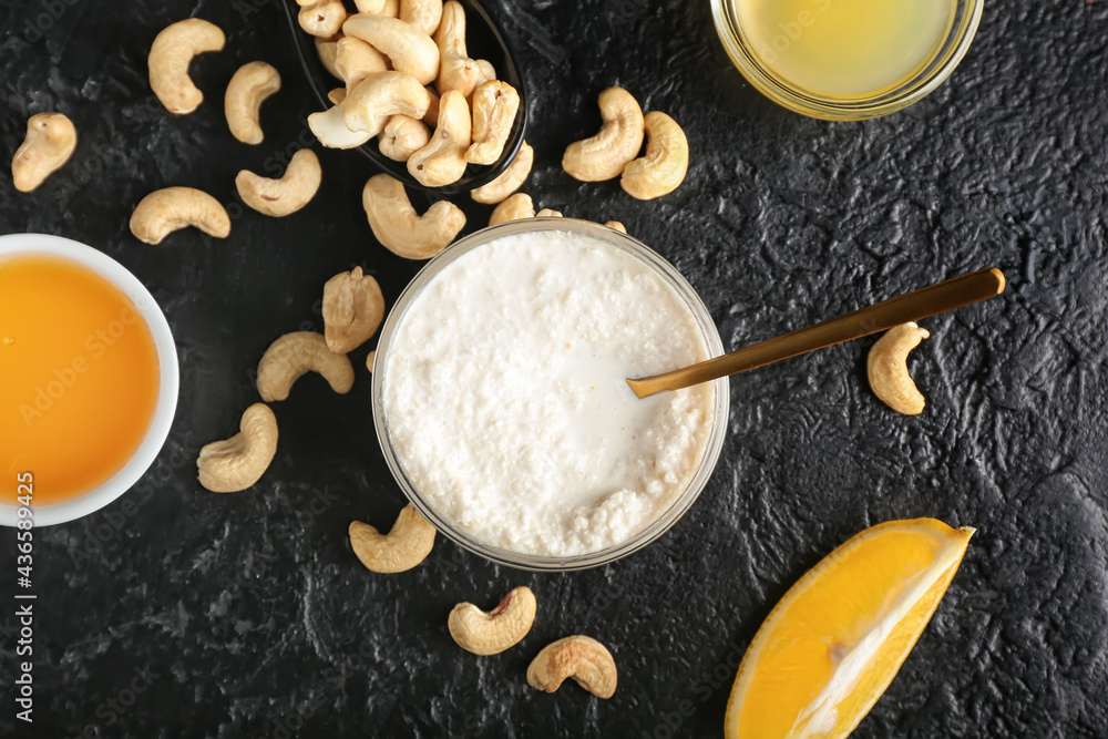 Bowl with cashew sour cream, nuts, honey and lemon juice on dark background