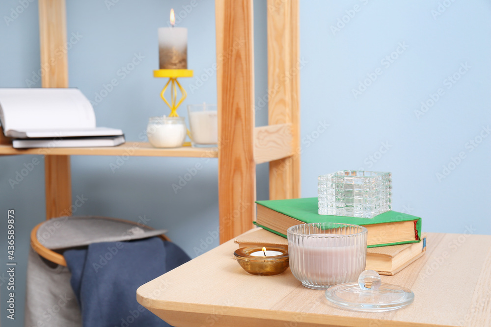 Table with books and candles near color wall